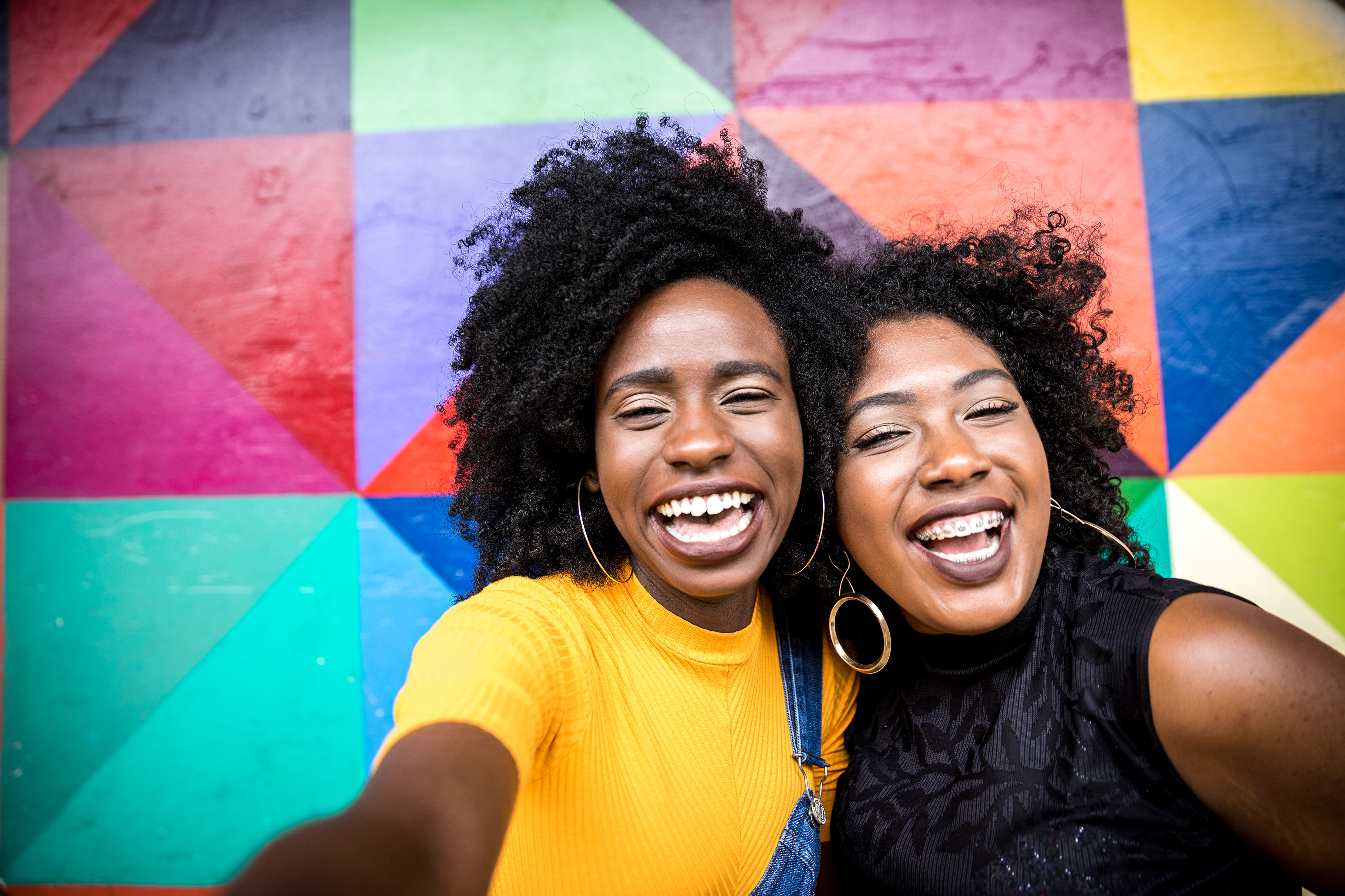 Two people smiling for the camera in front of a colorful fractal backdrop